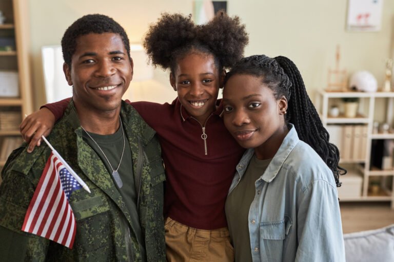 Smiling Black military father holding an American flag with his daughter and wife, symbolizing family sacrifice