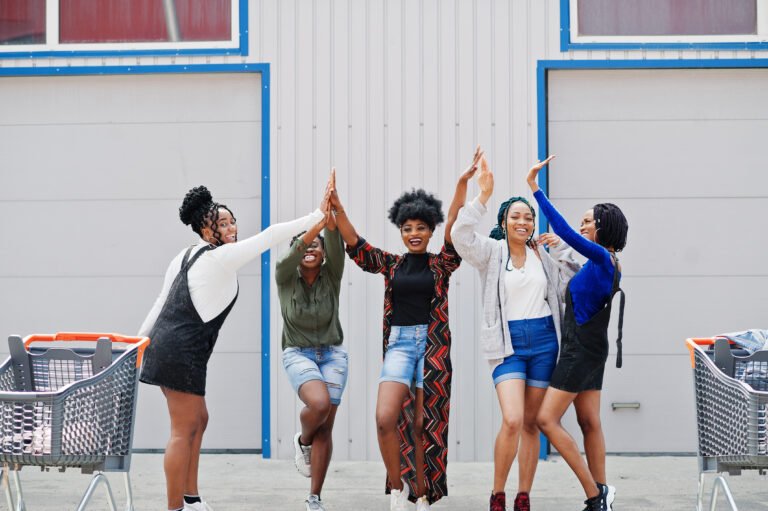 Five Black women celebrating joyfully with a high-five, symbolizing strength, pride, and unity